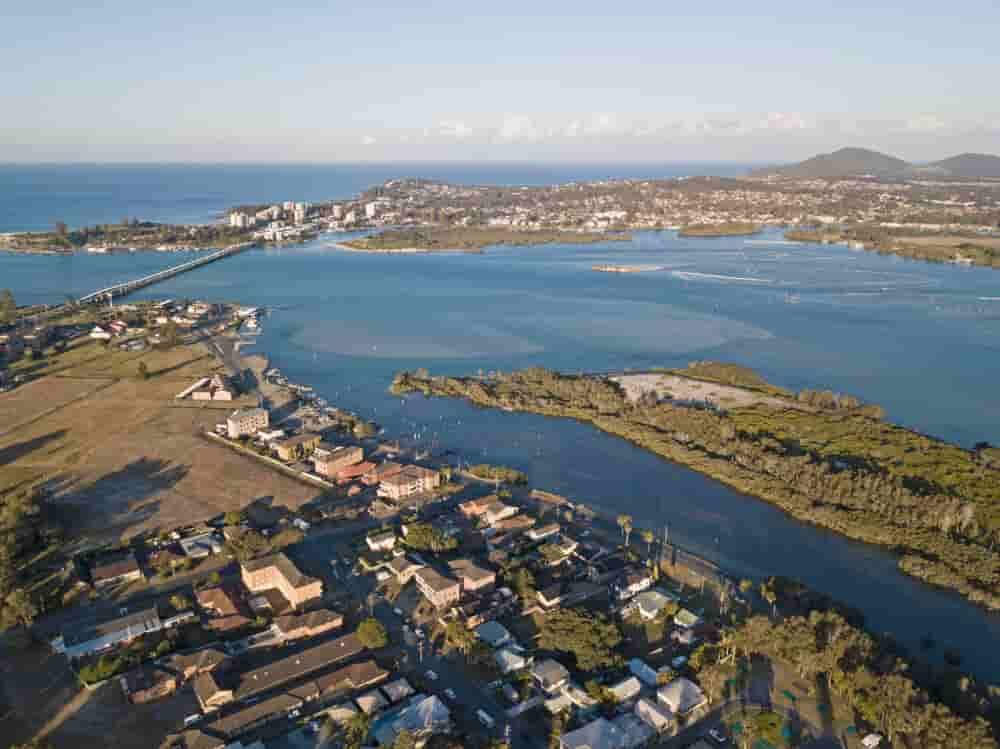 An Aerial View Of A Large Body Of Water Surrounded By Houses And Trees — Caprice Home Additions In Tuncurry, NSW