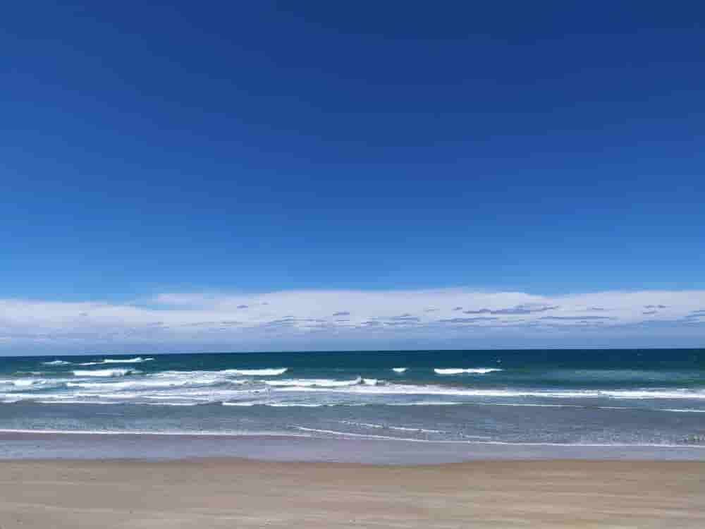 A Beach With A Blue Sky And Waves Coming In On A Sunny Day — Caprice Home Additions In Old Bar, NSW