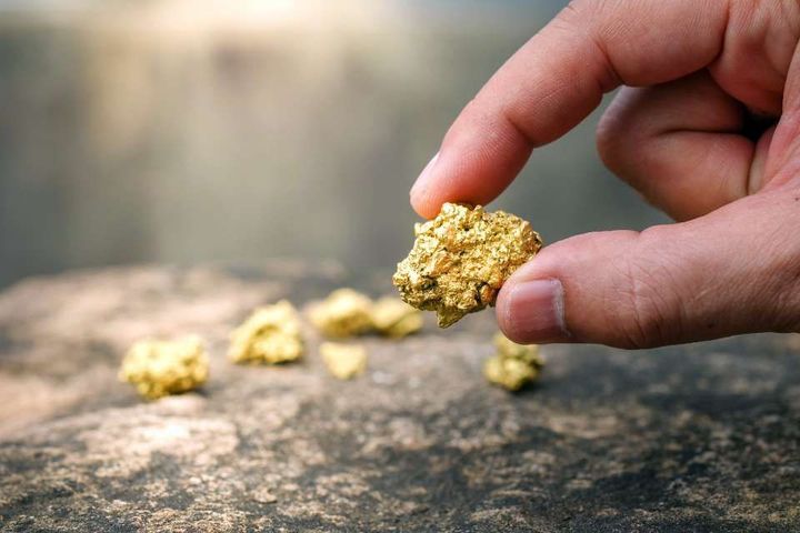 A person is holding a piece of gold in their hand.