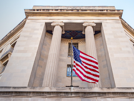 Edificio del Departamento de Justicia de Estados Unidos con bandera, altas columnas y vista exterior.
