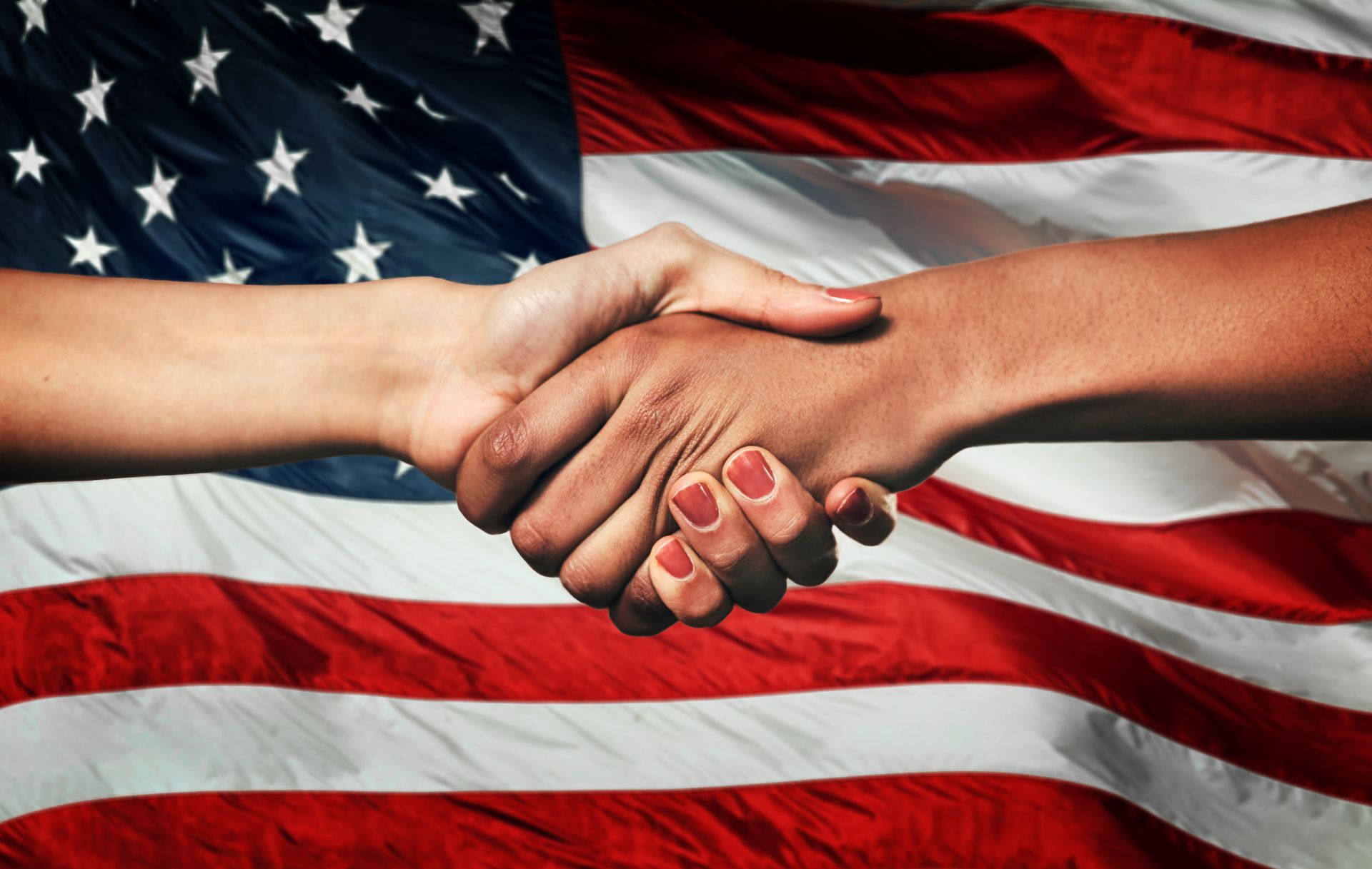 Hands clasped in a handshake against a backdrop of the American flag.