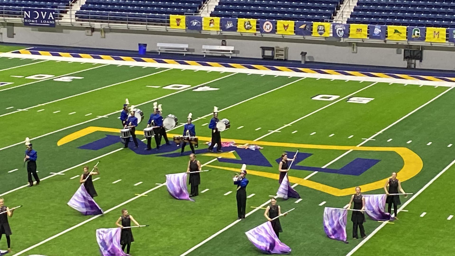 A marching band color guard is performing on a football field