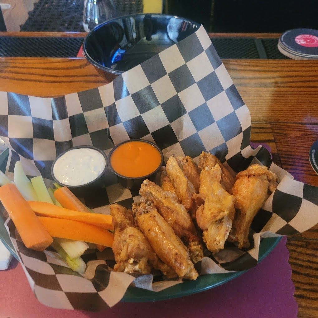 A bowl of chicken wings with carrots and ranch dressing
