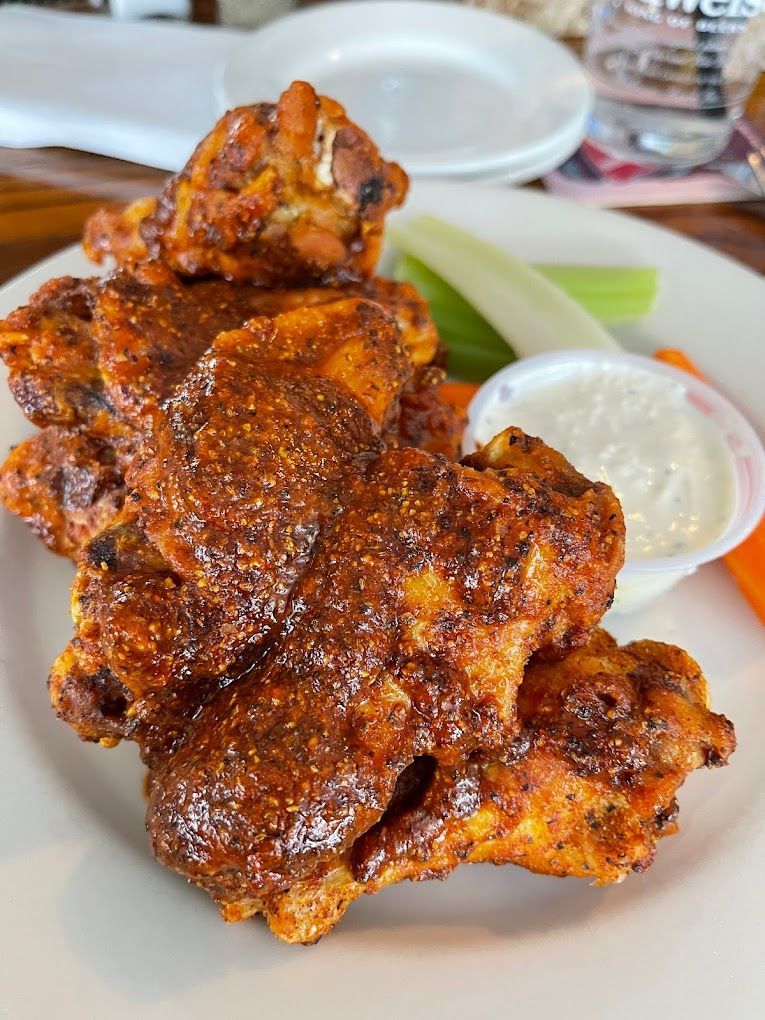 A white plate topped with chicken wings and vegetables.