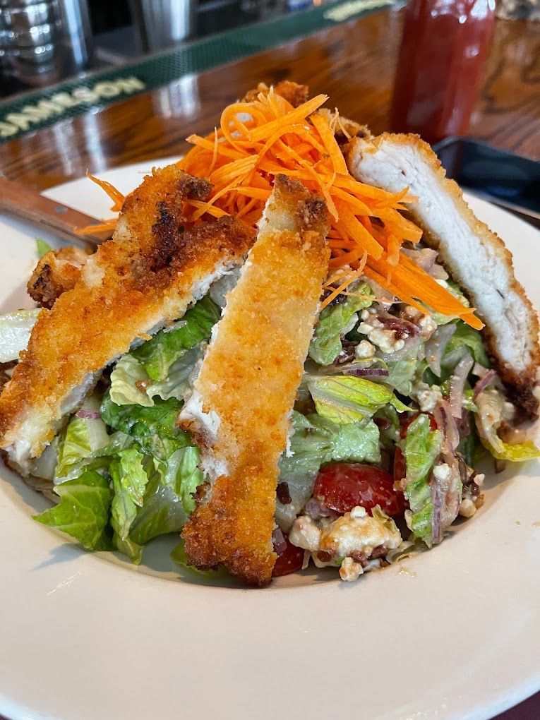 A close up of a salad with chicken and carrots on a plate.