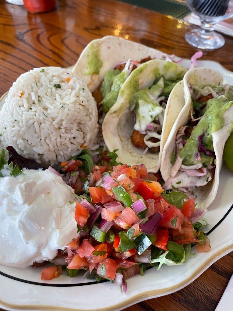 A plate of food with tacos , rice and salsa on a table.