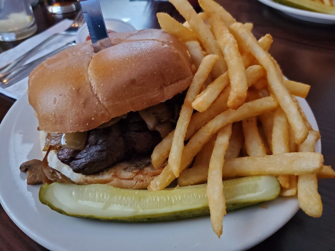 A sandwich with french fries and a pickle on a plate