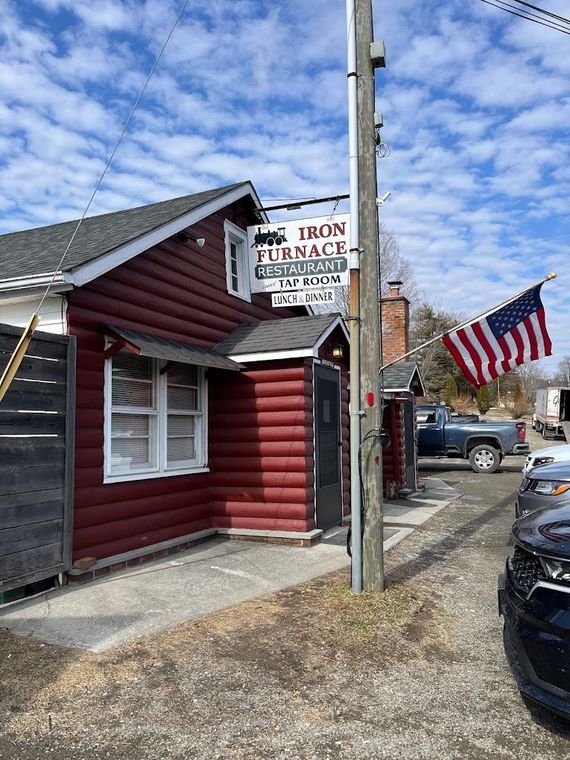 A red log cabin with a sign on the side of it.