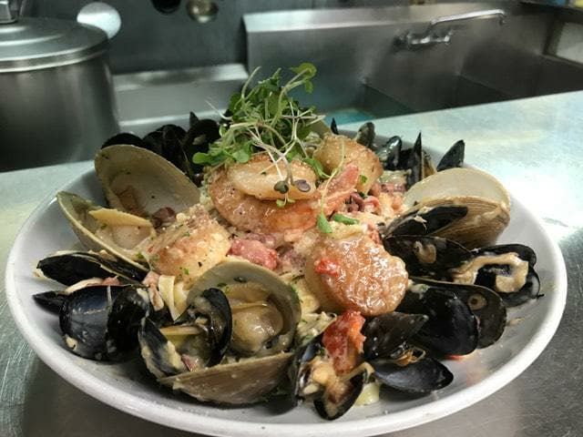 A white plate topped with seafood and rice on a counter.