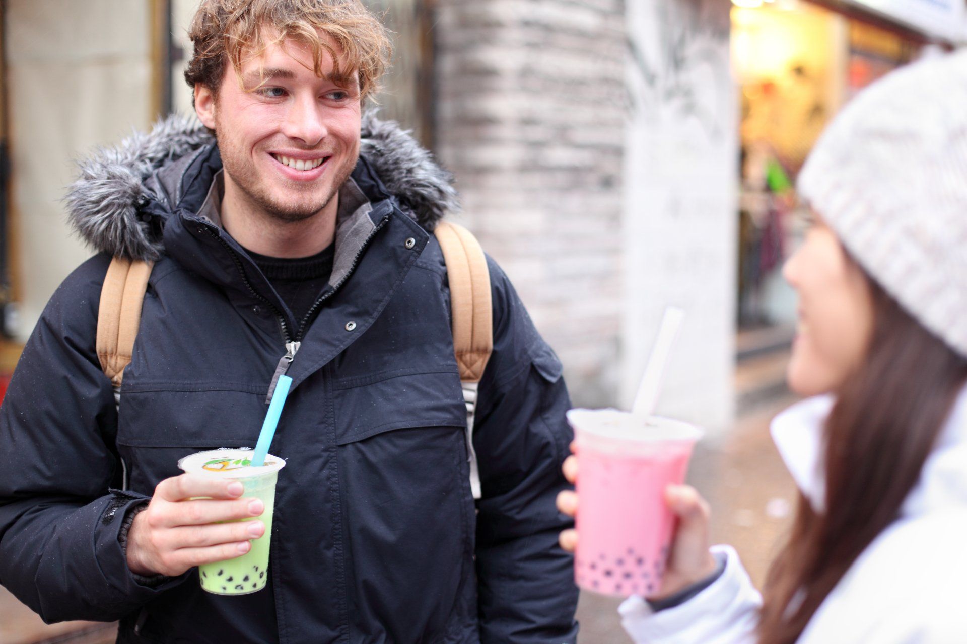 Friends in city drinking bubble tea or pearl milk tea smiling happy and talking