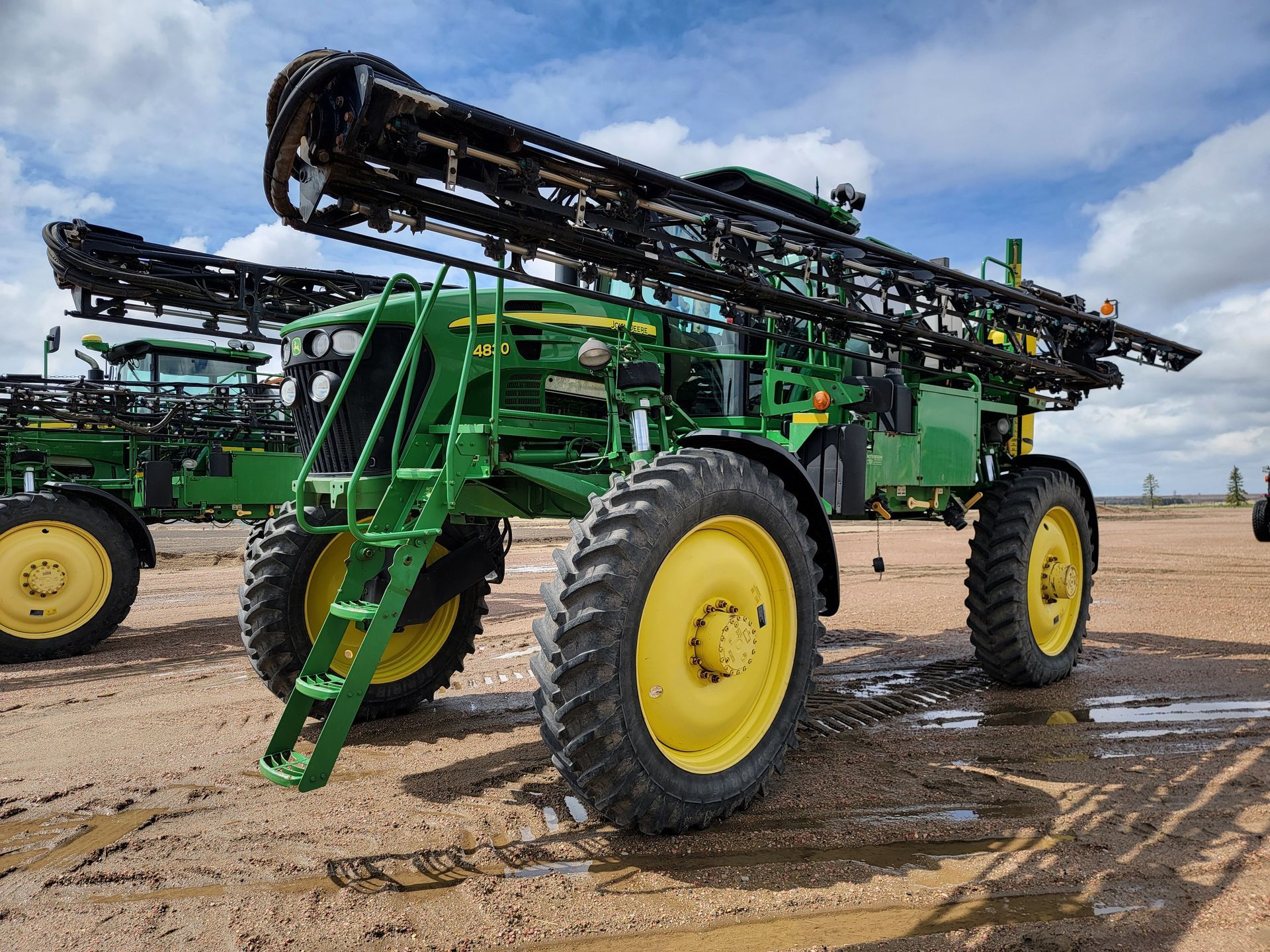 Green and yellow John Deere agricultural sprayer in a field.