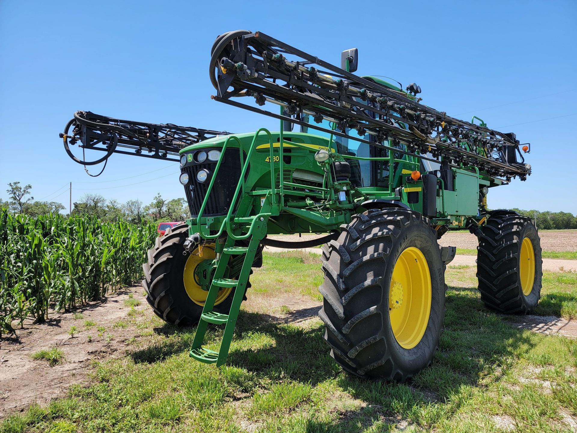 Green and yellow John Deere agricultural sprayer in a field.
