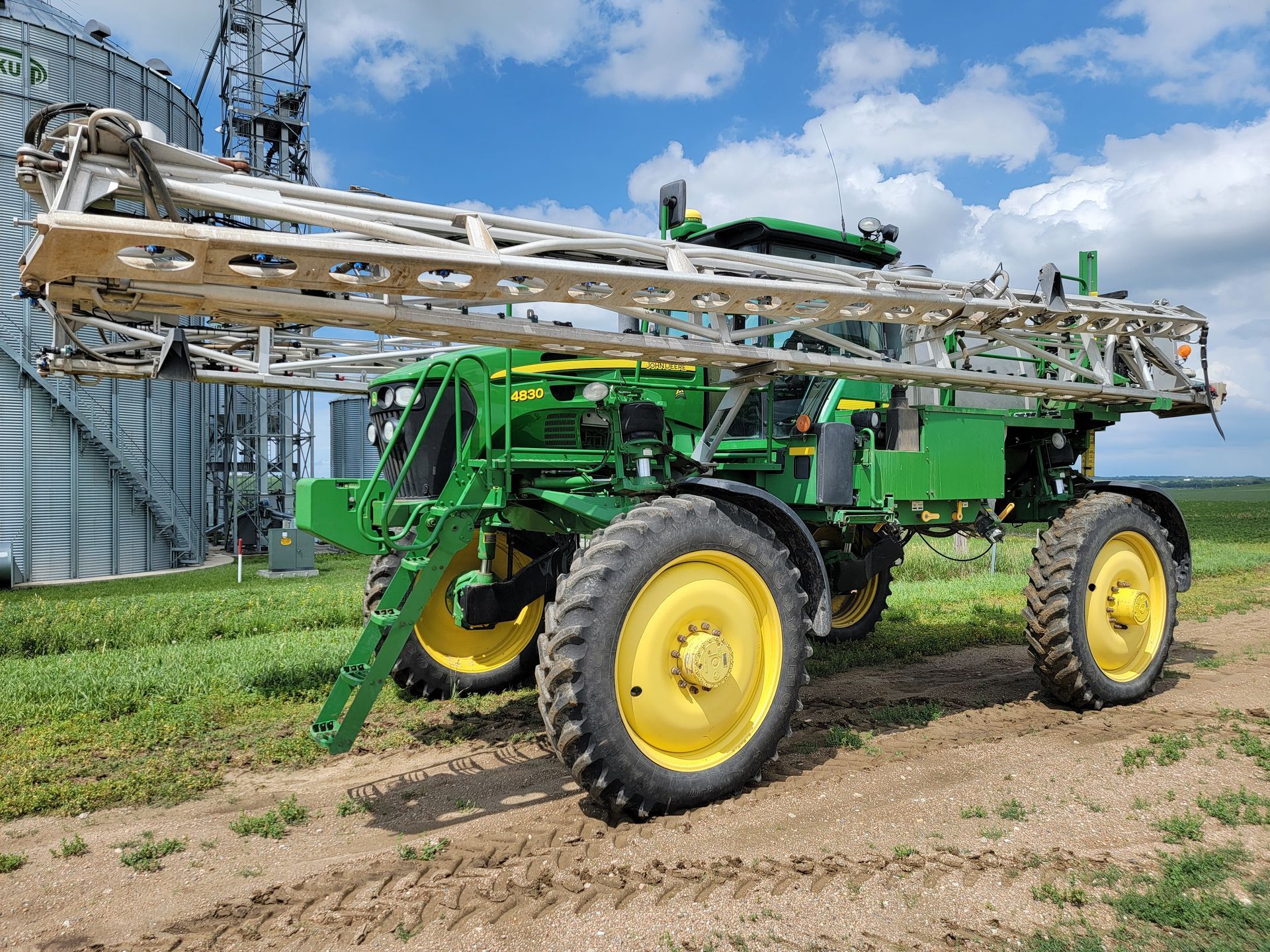 Green and yellow John Deere agricultural sprayer in a field.