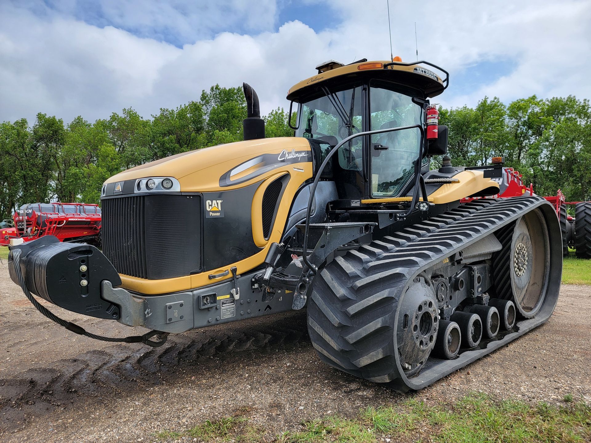 Yellow and black Challenger tractor with tracks on gravel.