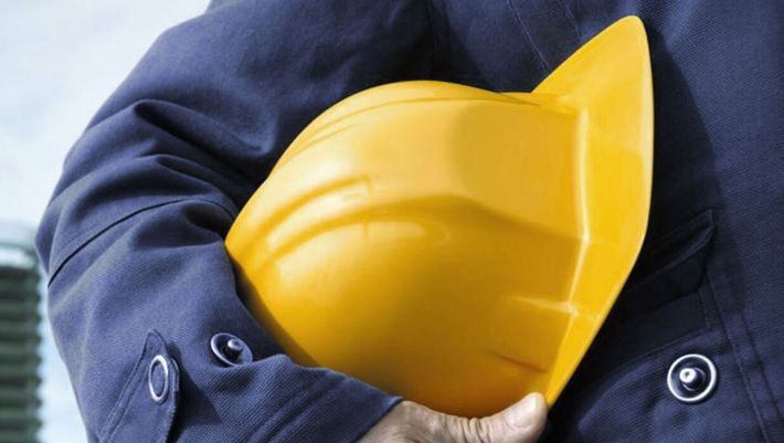 man in a work jumpsuit holding a hard hat