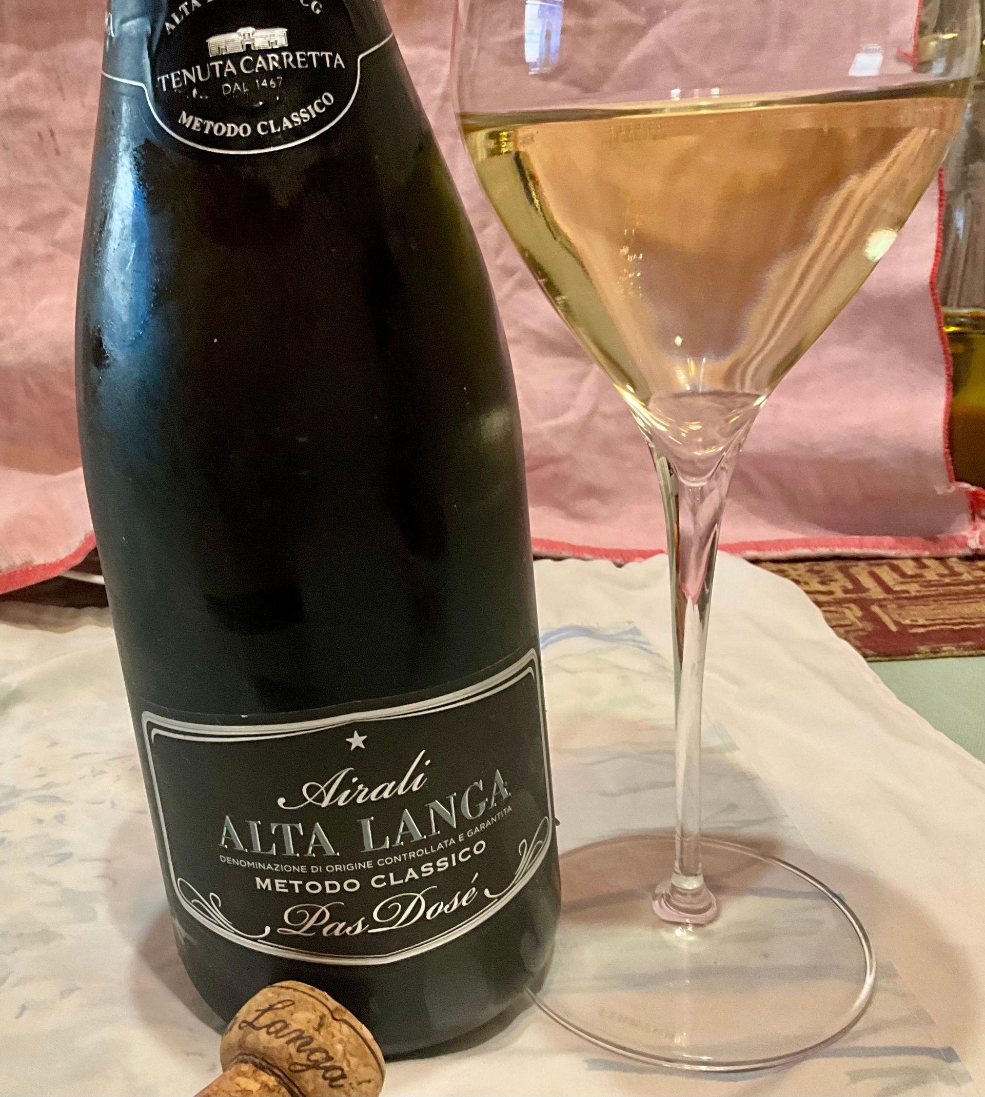 eine Flasche Tenuta Carretta Airali Alta Langa Pas Dosé 2018a steht neben einem gefüllten Weinglas