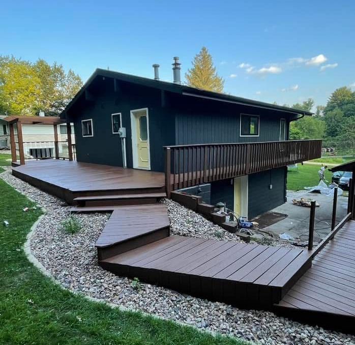 A black house with a wooden deck and stairs