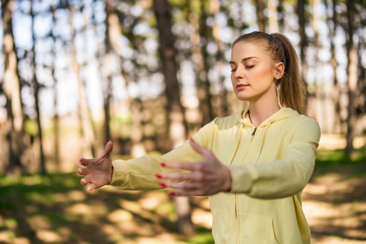 Una mujer está practicando Qi Gong en el bosque.