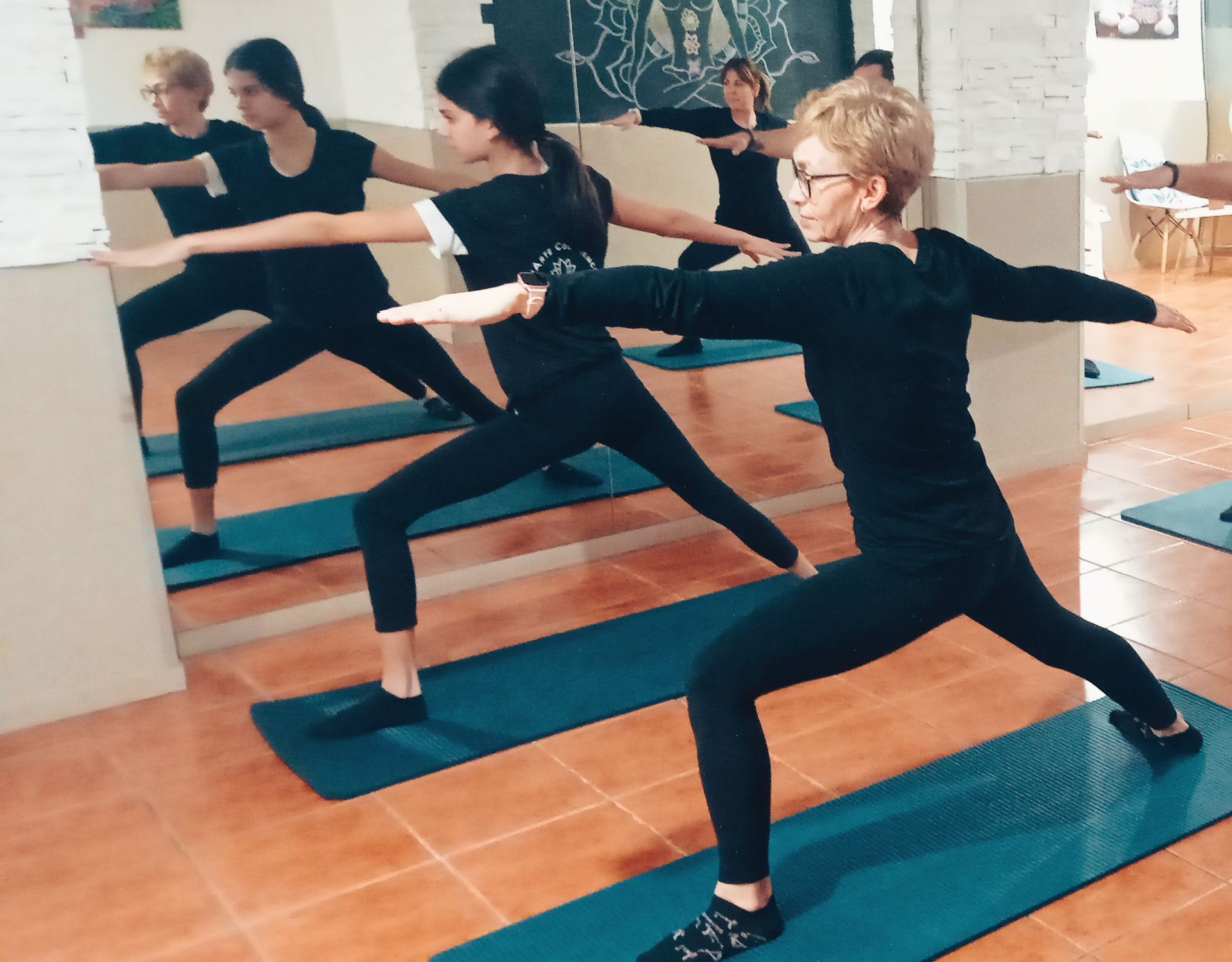 Un grupo de personas está haciendo yoga frente a un espejo.