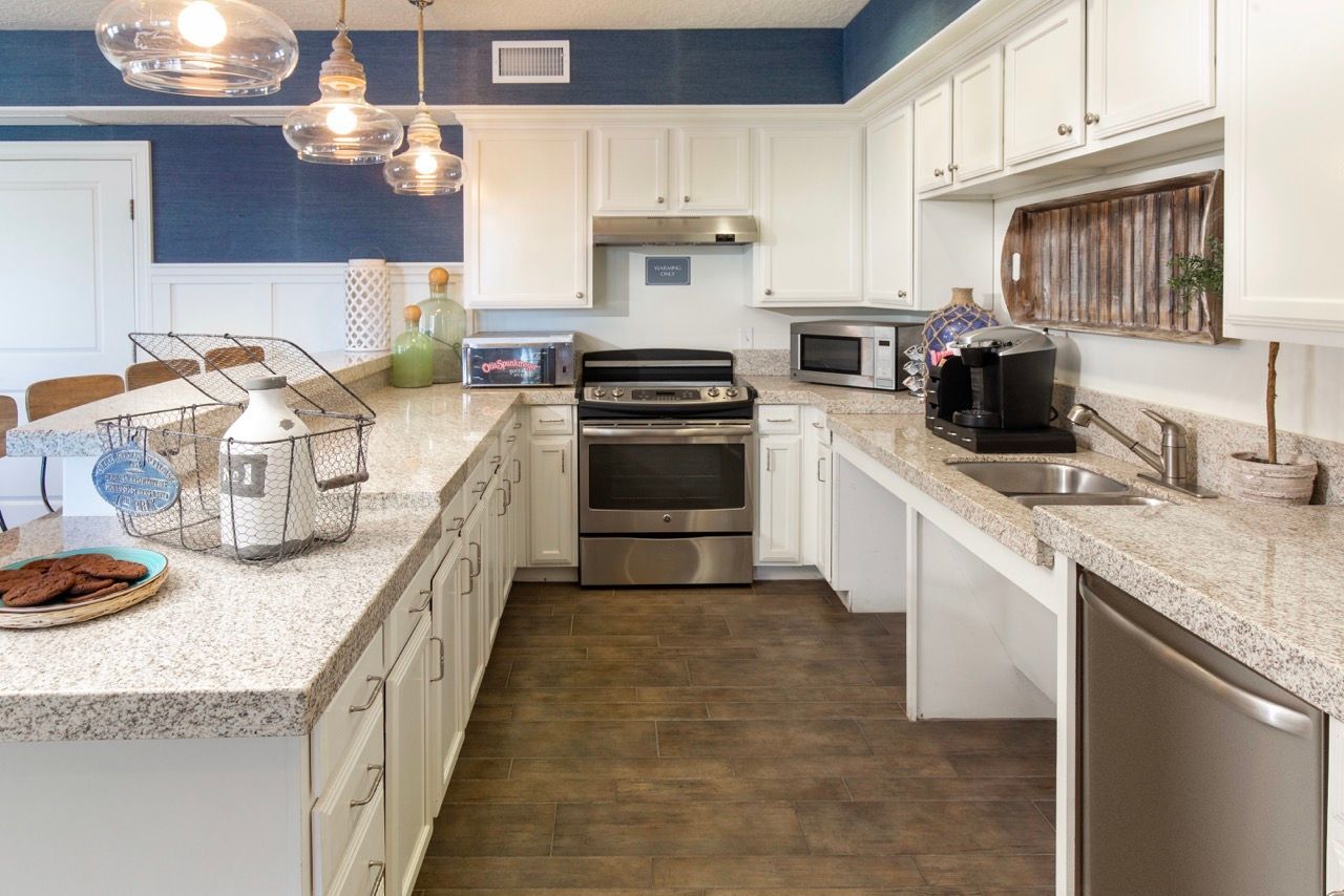 Modern apartment kitchen with white cabinets, granite countertops, and stainless steel appliances.
