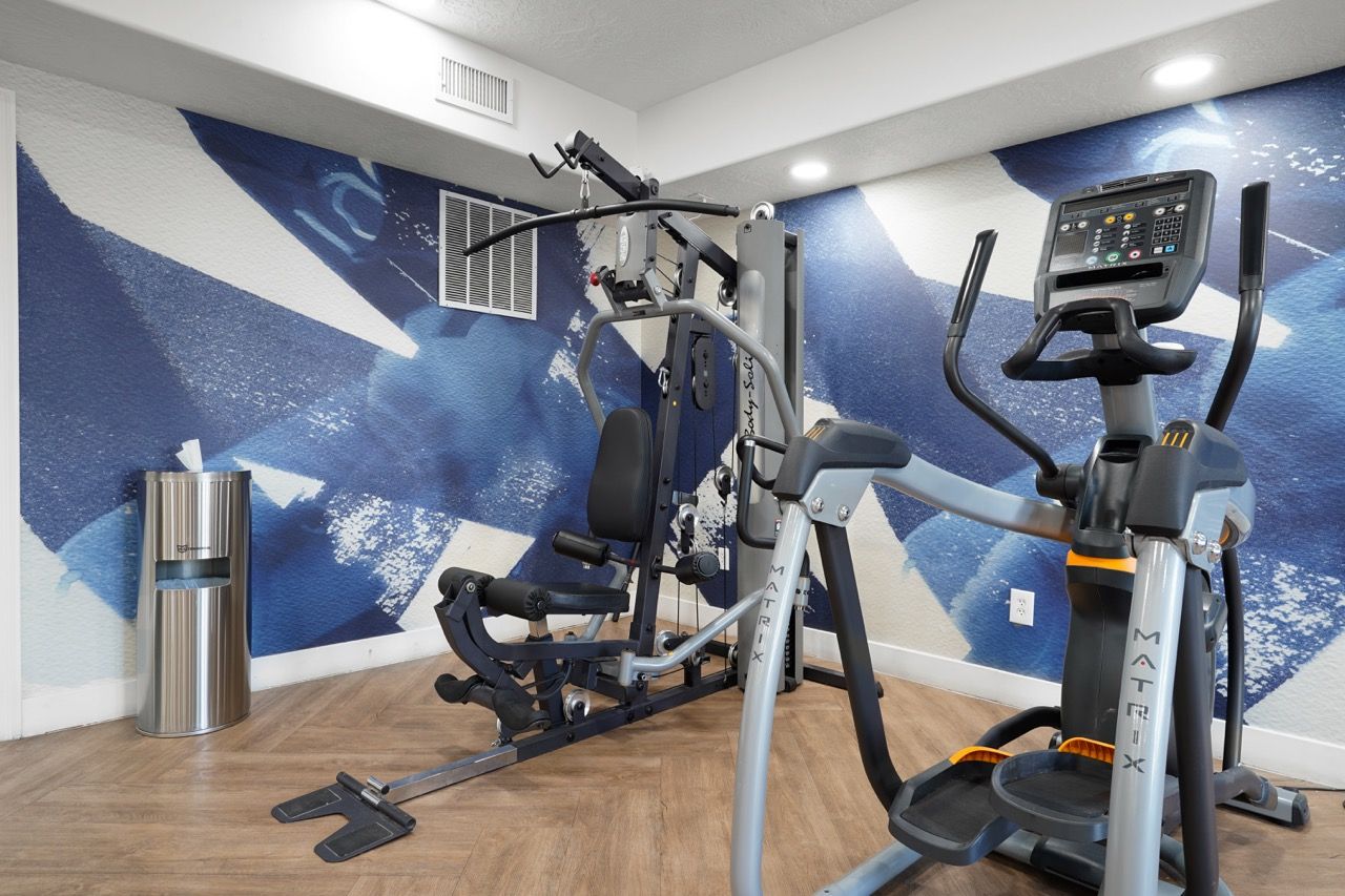 Indoor fitness center with cardio machine and weight training equipment against a blue wall.