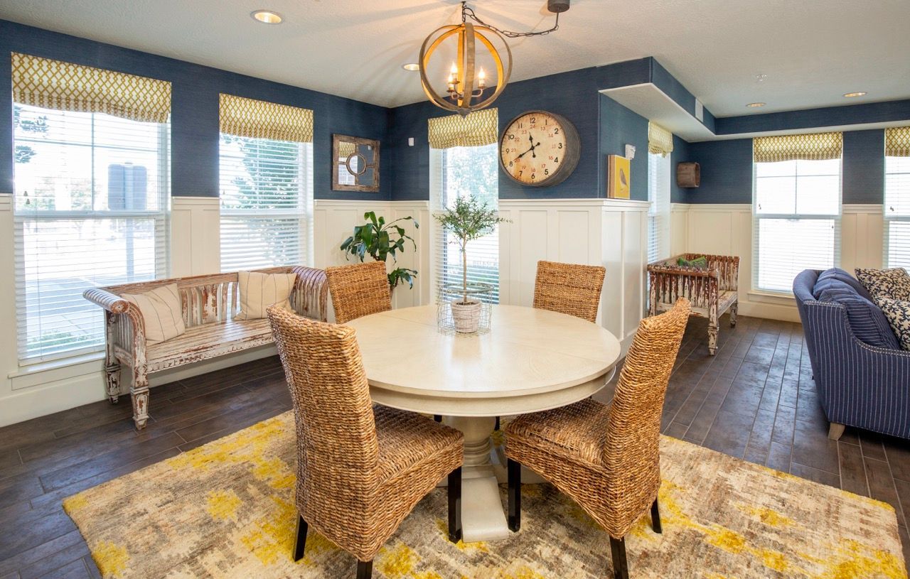 Common lounge with a round dining table, wicker chairs, blue walls, and large windows.