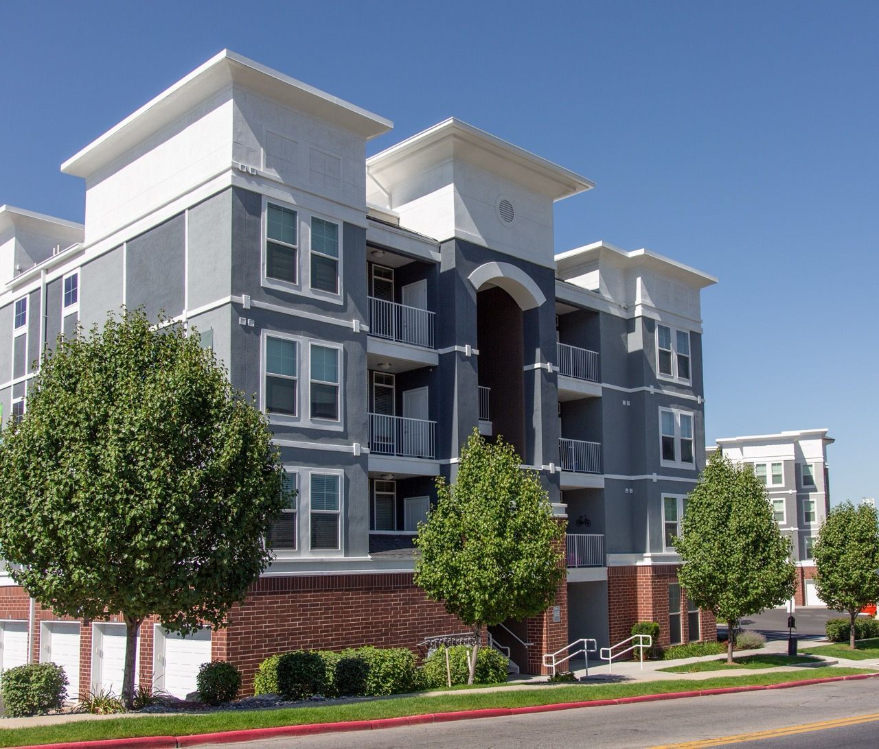 Exterior view of a modern apartment building with balconies and trees.