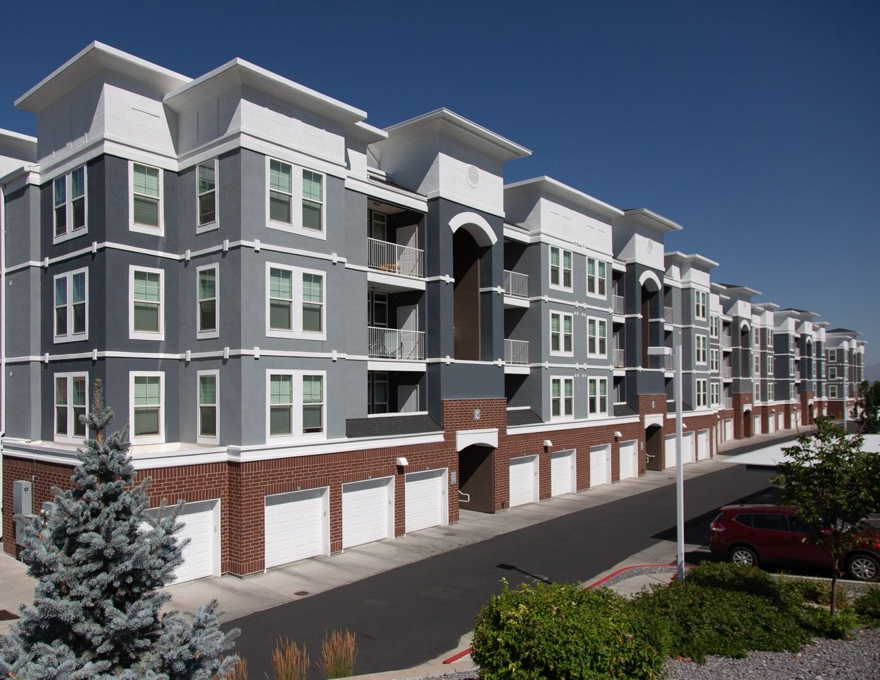 Exterior view of a modern multi-story apartment building with row of garages.