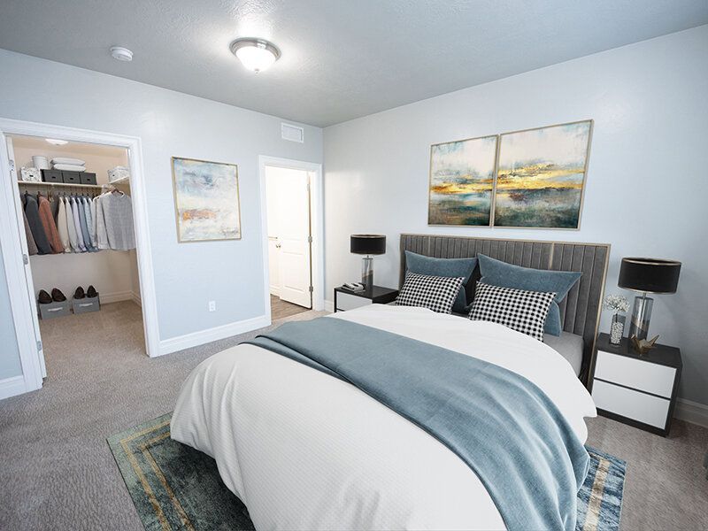 Bedroom in an apartment with a large bed, blue-gray bedding, and an adjacent walk-in closet.