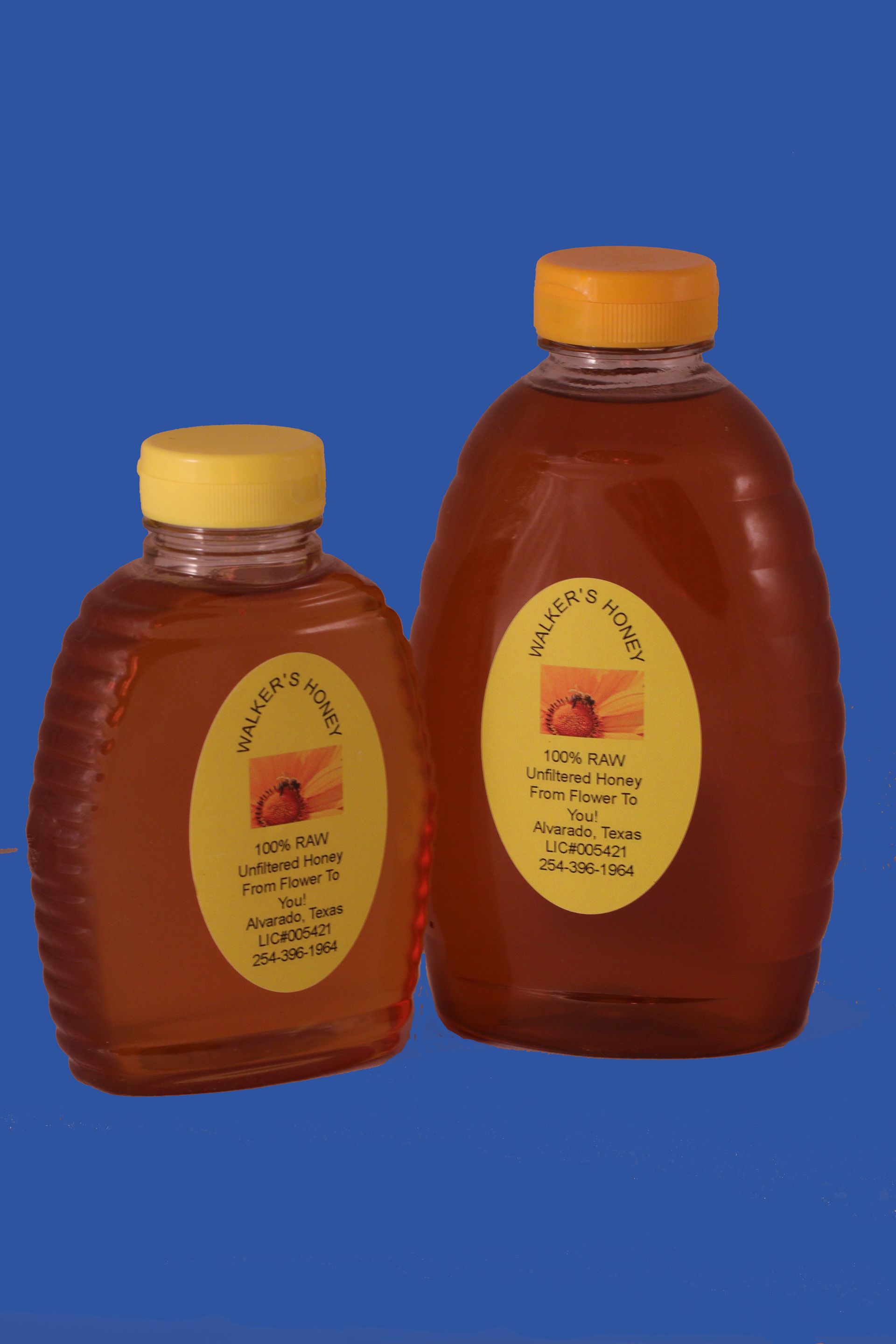 Three honey bottles with yellow labels on a reflective surface.