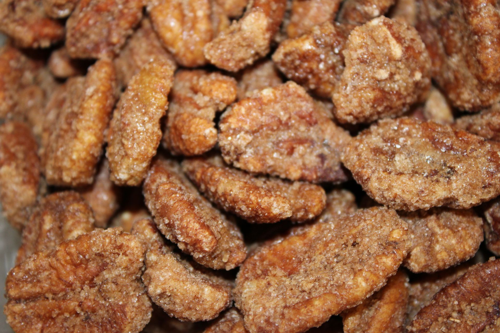 Sugar-coated pecans; close-up shot showing multiple nuts covered in a brown, crystalline coating.