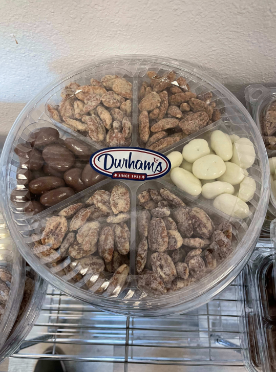 Clear circular tray of mixed nuts from Durham's, including chocolate-covered, sugared, and plain nuts.