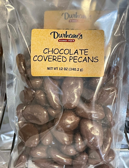 Bag of Durham's chocolate covered pecans, brown label with text and brown candy inside clear bag.