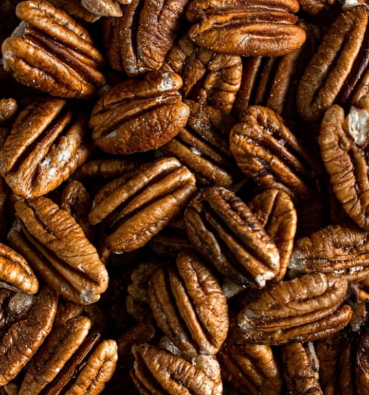 Pile of shelled pecan halves, brown and textured.