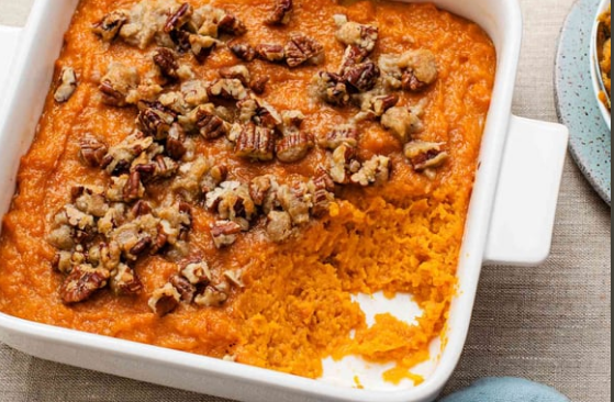 Sweet potato casserole with pecan topping in a white baking dish.