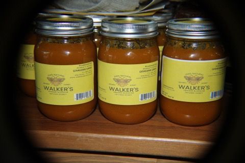 Jars of Walker's brand preserves, filled with brown contents, sit on a shelf. Yellow labels and silver lids are visible.