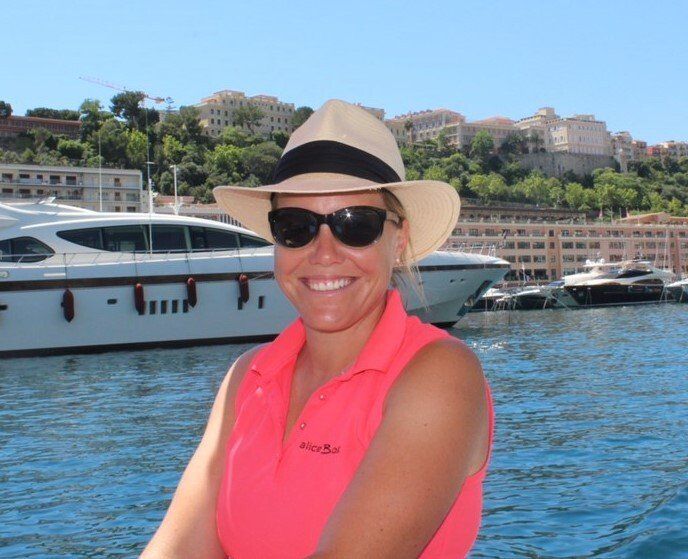A woman wearing a hat and sunglasses sits on a boat.