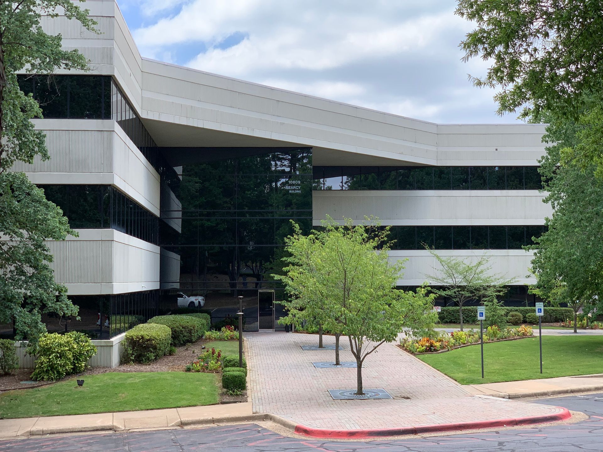 A large white building with a lot of windows is surrounded by trees and grass.