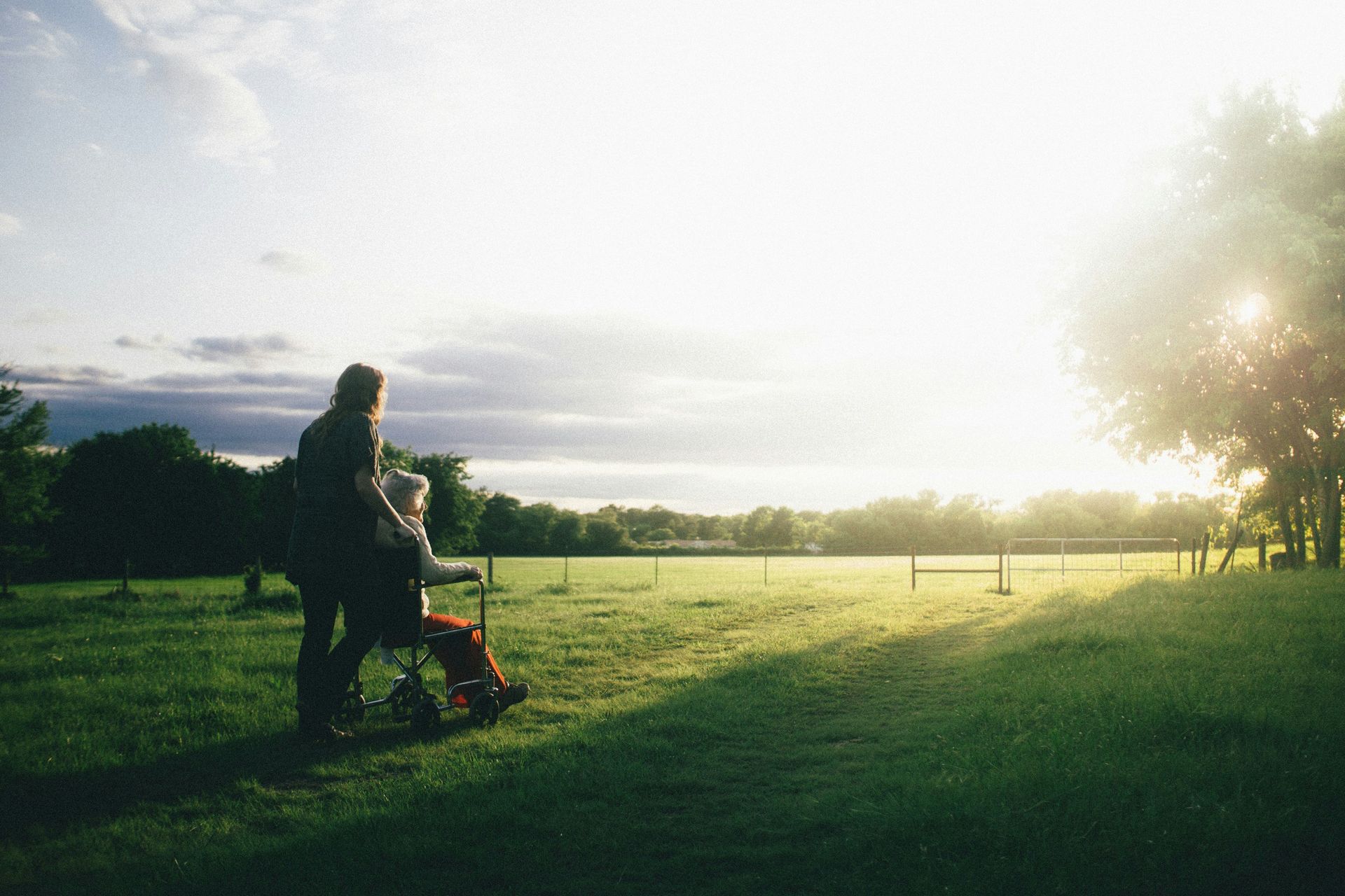 Older woman in wheelchair looking out the sunset