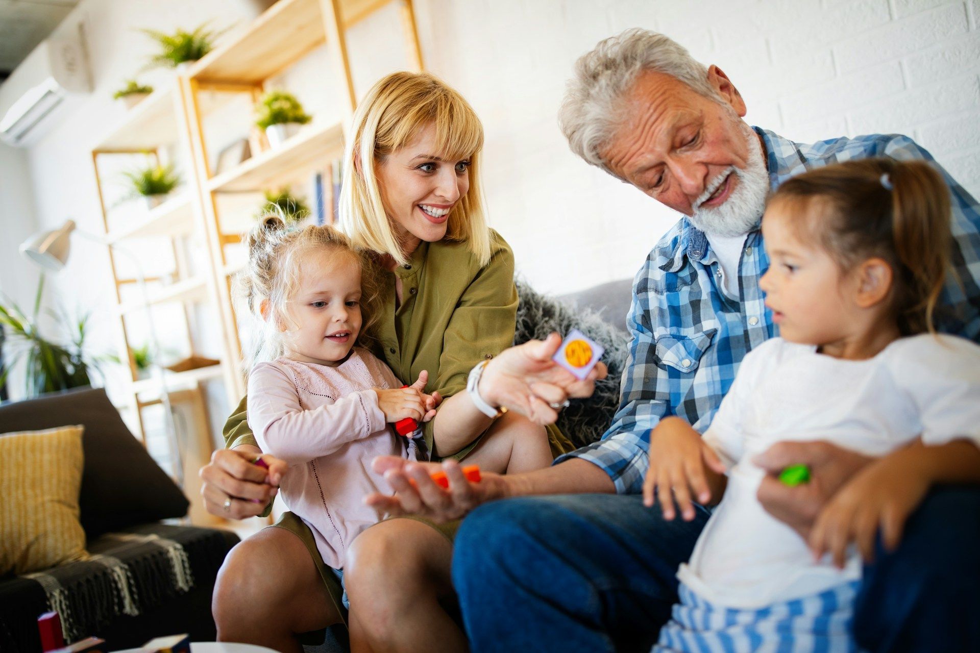 Family gathered on a couch, smiling and playing with a baby in a bright living room