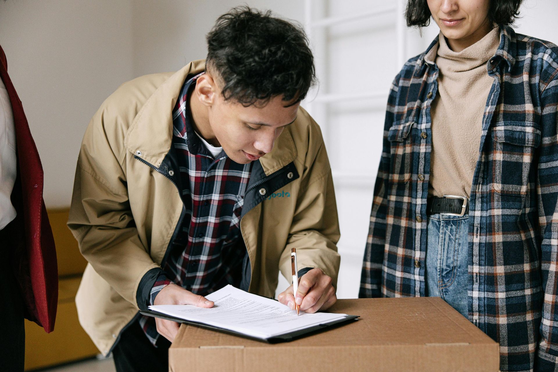 A man is signing a document next to a box.