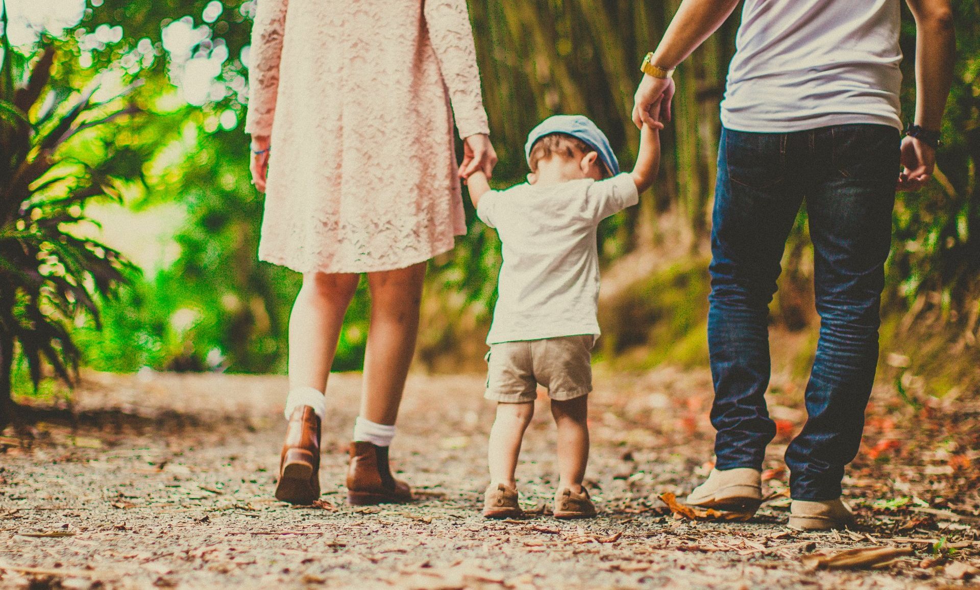 A family is walking down a dirt road holding hands.