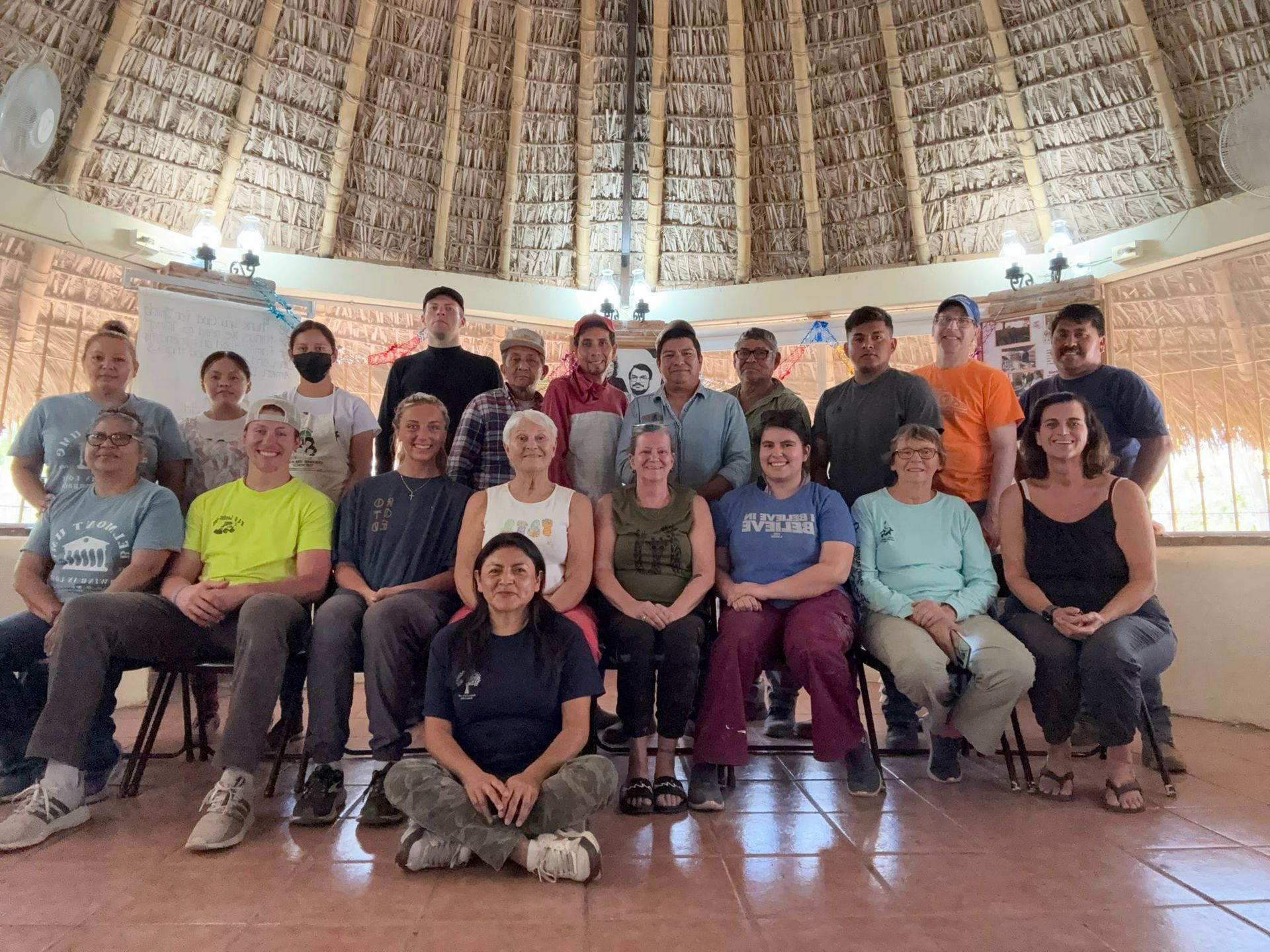 A group of people are posing for a picture in a room with a thatched roof.