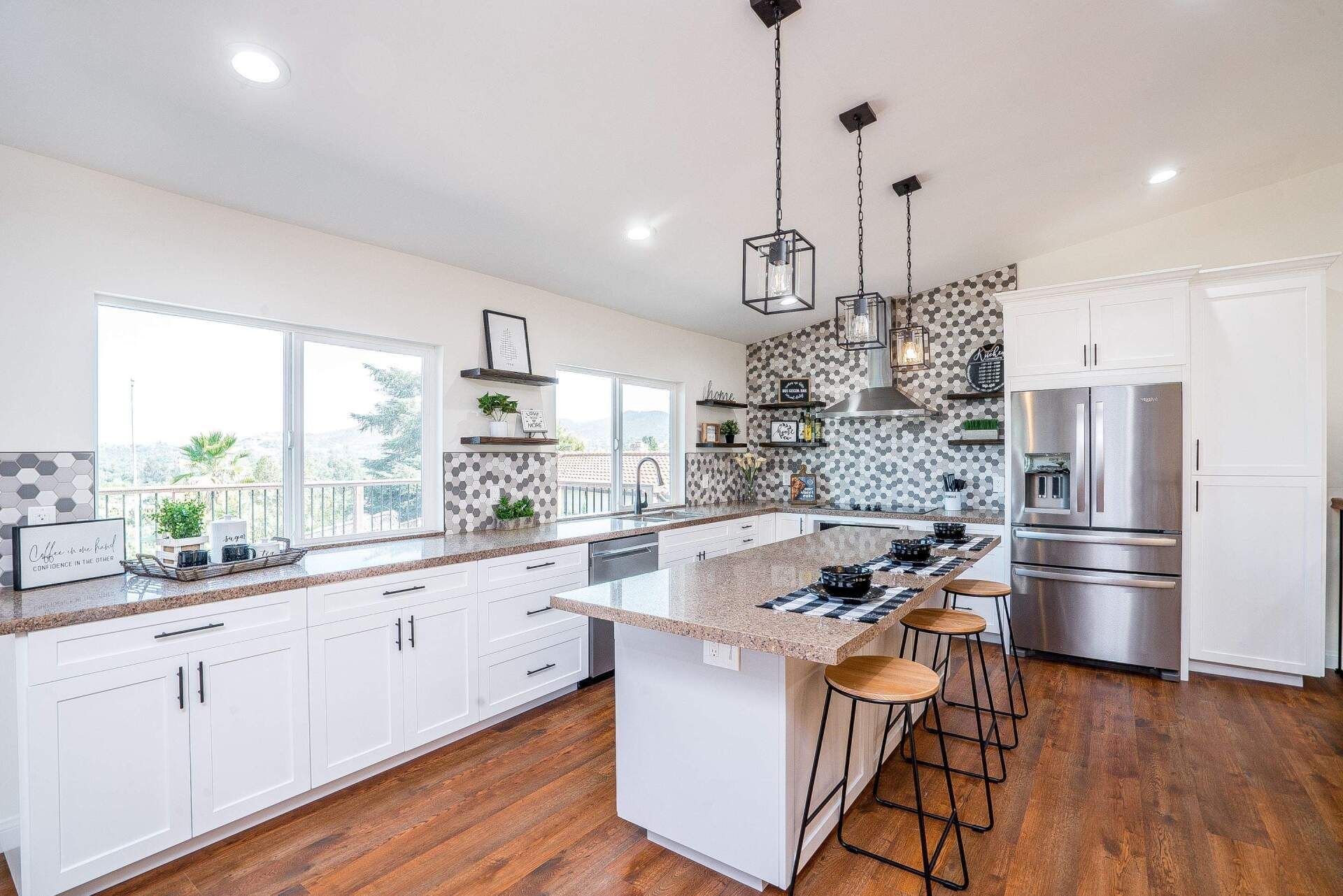 Modern kitchen with white cabinets, stainless steel appliances, and a granite countertop island.
