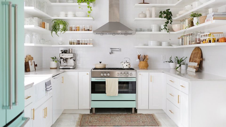 White kitchen with open shelving and mint-green appliances; plants and decor arranged throughout.