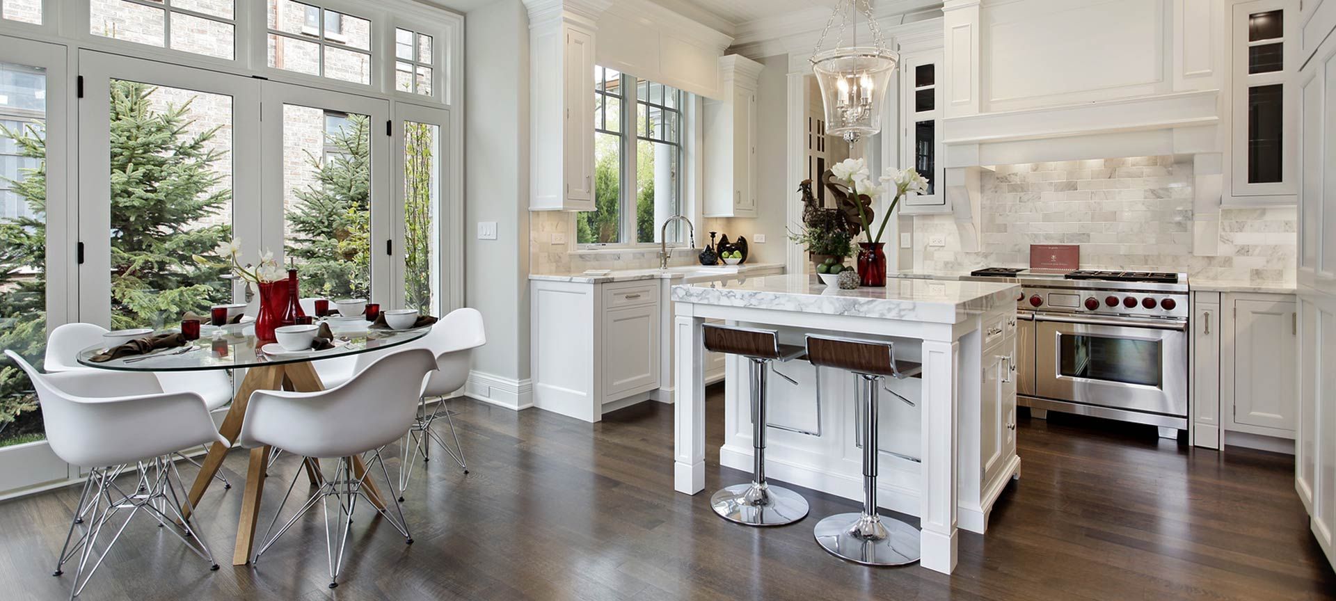 Bright, white kitchen with large windows and a glass dining table.