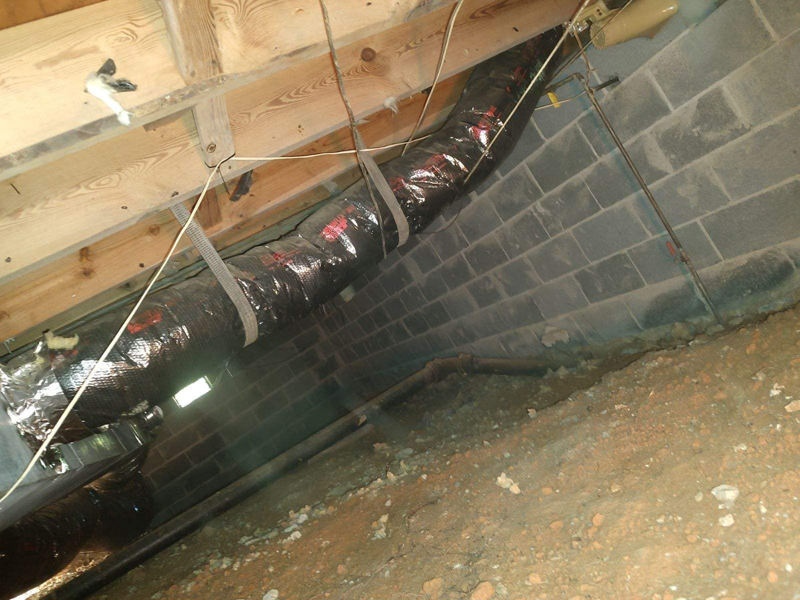 A hose is hanging from the ceiling of a basement.