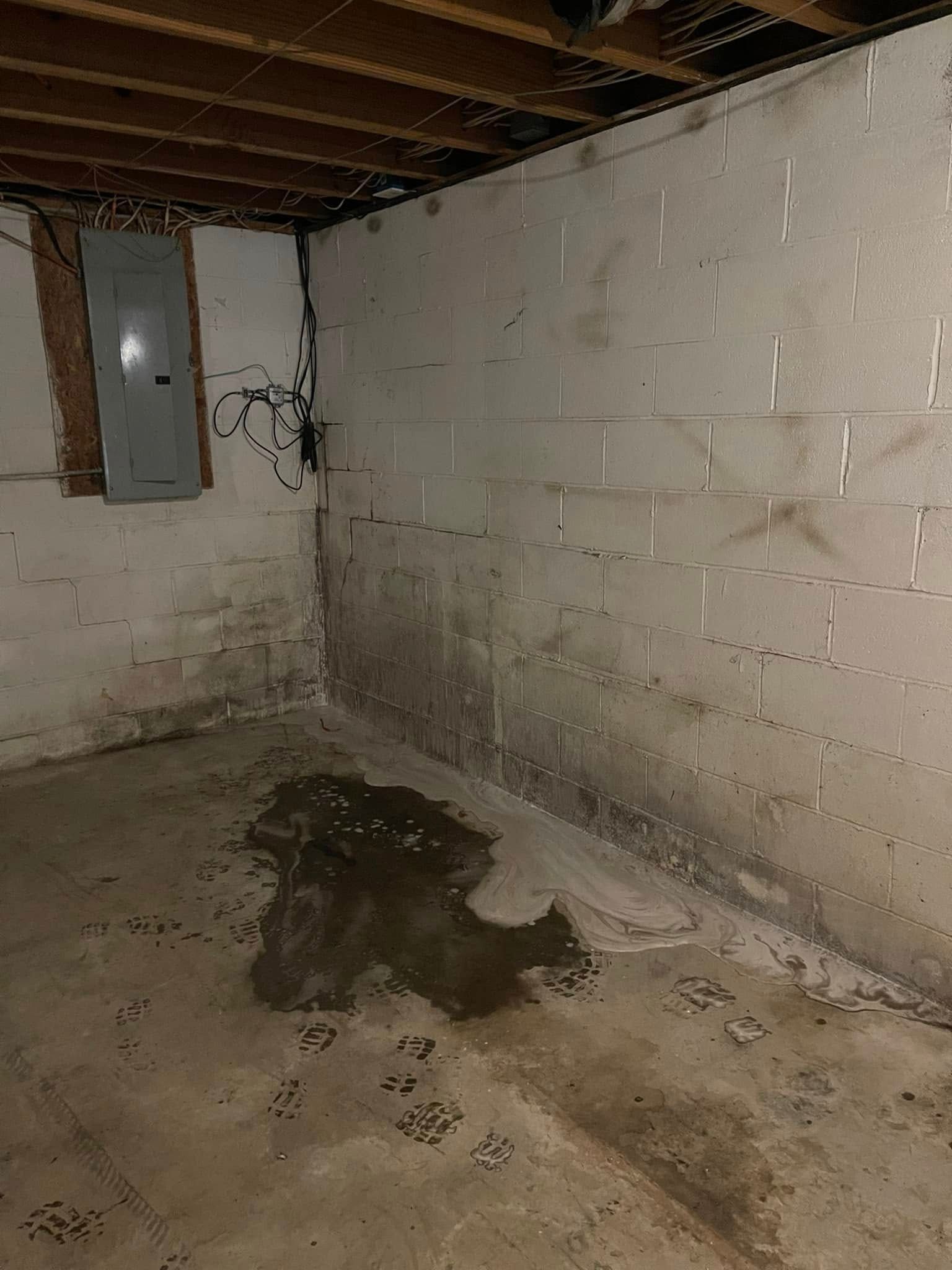 A dirty basement with a brick wall and a window.