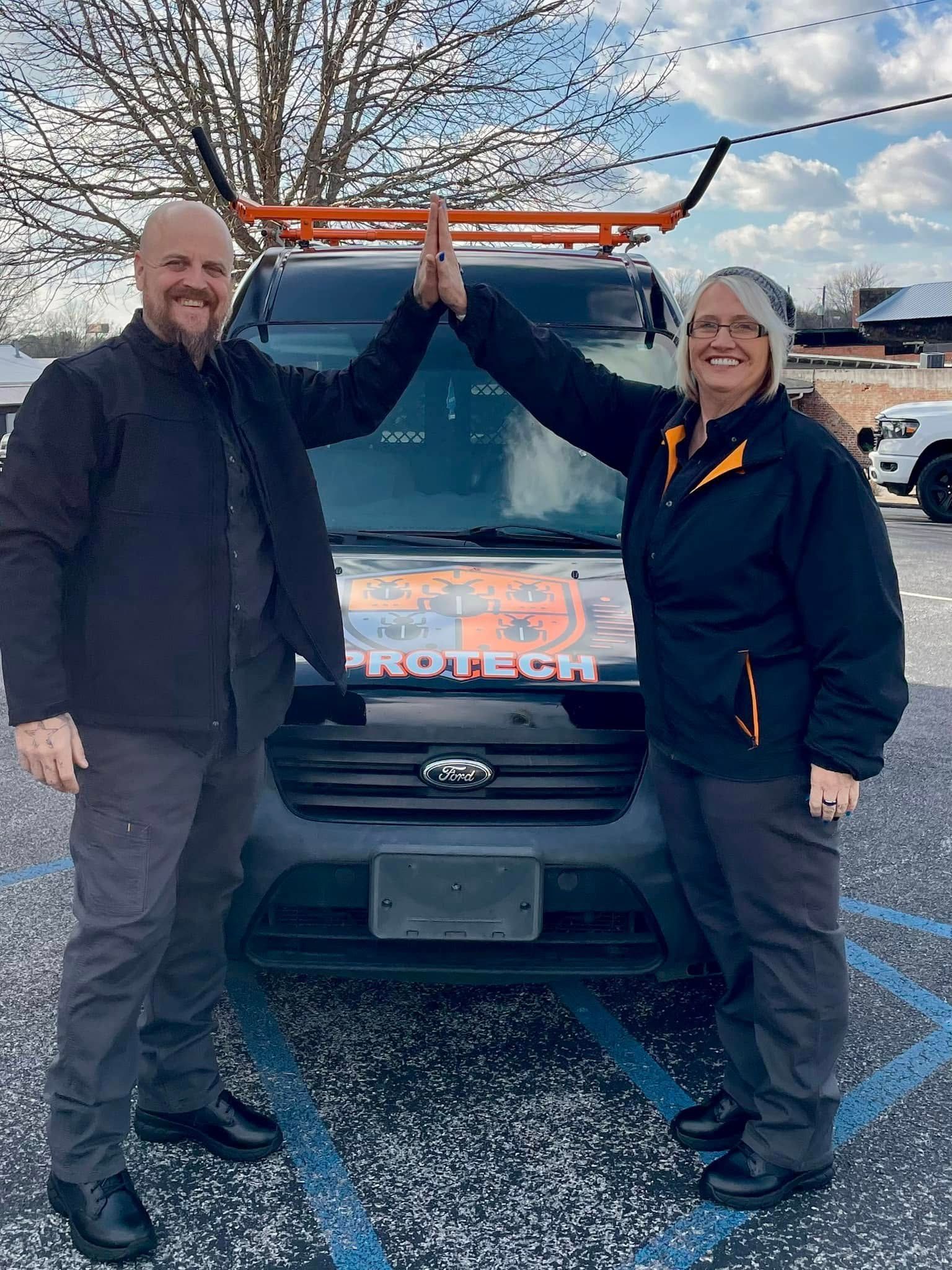 A man and a woman are giving each other a high five in front of a van.