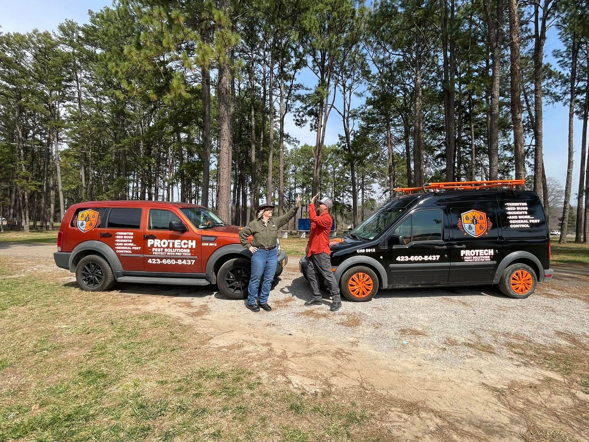 Two men are standing next to two trucks in a parking lot.